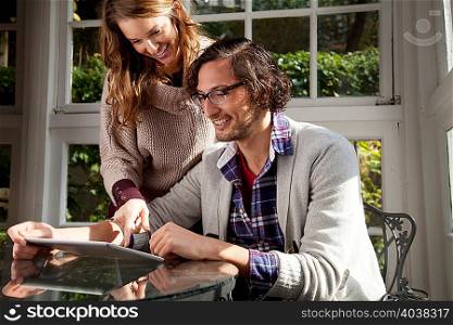 Couple using tablet computer at table