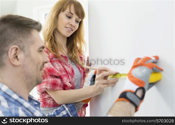 Couple using tape measure on wall