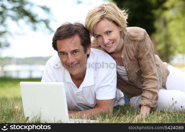 Couple using their laptop in a field
