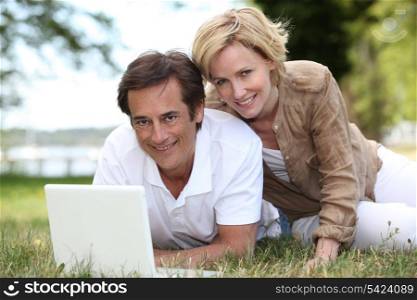 Couple using their laptop in a field