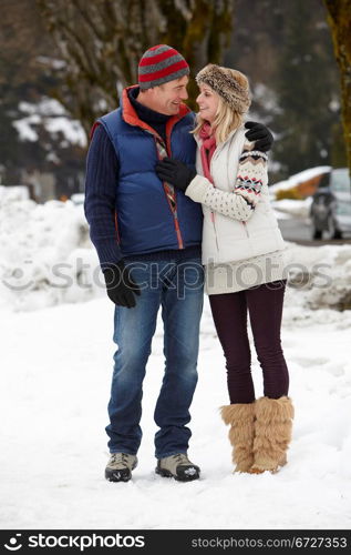 Couple Walking Along Snowy Street In Ski Resort