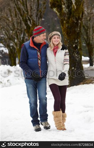 Couple Walking Along Snowy Street In Ski Resort