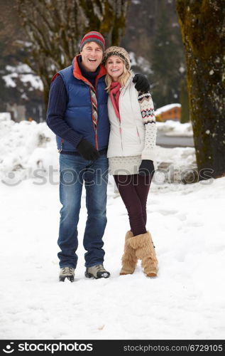 Couple Walking Along Snowy Street In Ski Resort