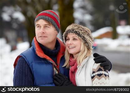 Couple Walking Along Snowy Street In Ski Resort