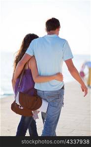 Couple walking and hugging on beach