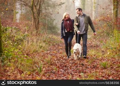 Couple Walking Dog Through Winter Woodland