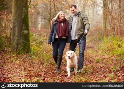 Couple Walking Dog Through Winter Woodland