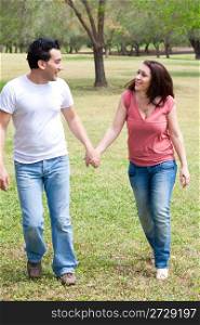 Couple walking holding hands and smiling at outdoor