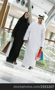 Couple walking in mall holding hands and smiling (selective focus)