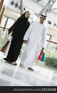 Couple walking in mall holding hands and smiling (selective focus)