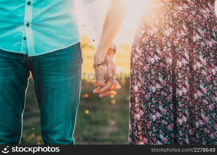 couple walking in nature at sunset holding hands