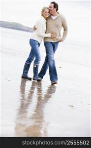 Couple walking on beach arm in arm smiling