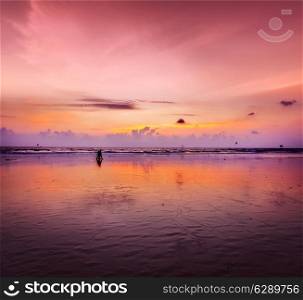 Couple walking on beach on romantic sunset. Baga beach. Goa, India