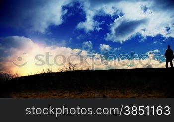 Couple walking on green meadow at sunset, time lapse clouds