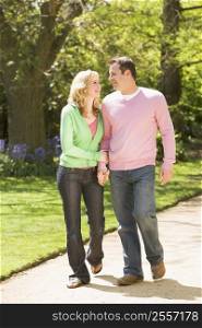 Couple walking on path holding hands smiling