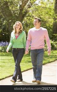 Couple walking on path holding hands smiling