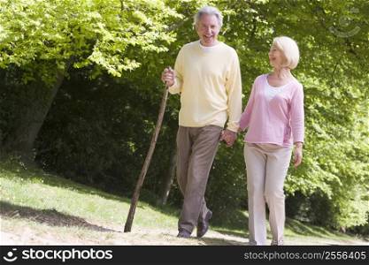 Couple walking on path in park holding hands and smiling