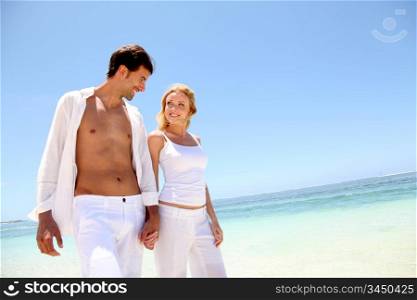 Couple walking on white sandy beach