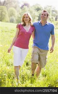 Couple walking outdoors holding flower smiling
