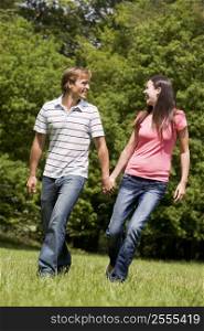 Couple walking outdoors holding hands smiling