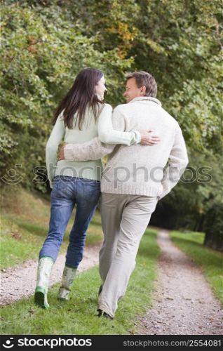 Couple walking outdoors on path in park smiling (selective focus)