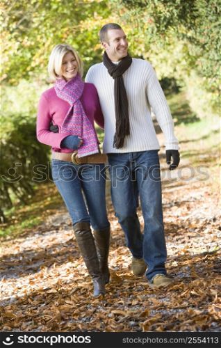 Couple walking outdoors on path in park smiling (selective focus)