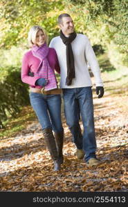 Couple walking outdoors on path in park smiling (selective focus)