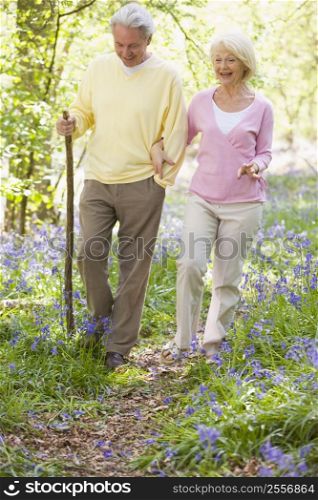 Couple walking outdoors with walking stick smiling