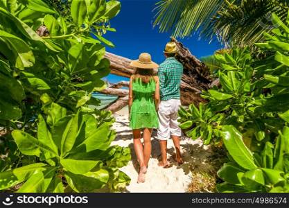 Couple walking to the beach Anse Source d'Argent among tropical foliage at Seychelles, La Digue.