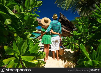 Couple walking to the beach Anse Source d&rsquo;Argent among tropical foliage at Seychelles, La Digue.
