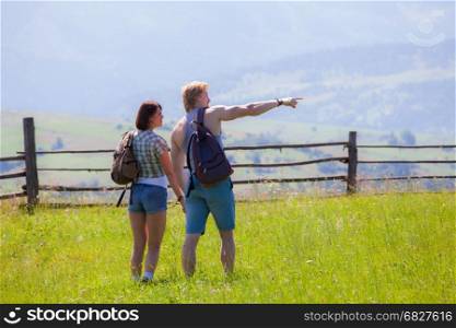 Couple walking together at the summer meadow and looking around countryside view