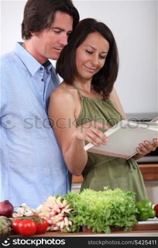 Couple watching cookbook in a kitchen