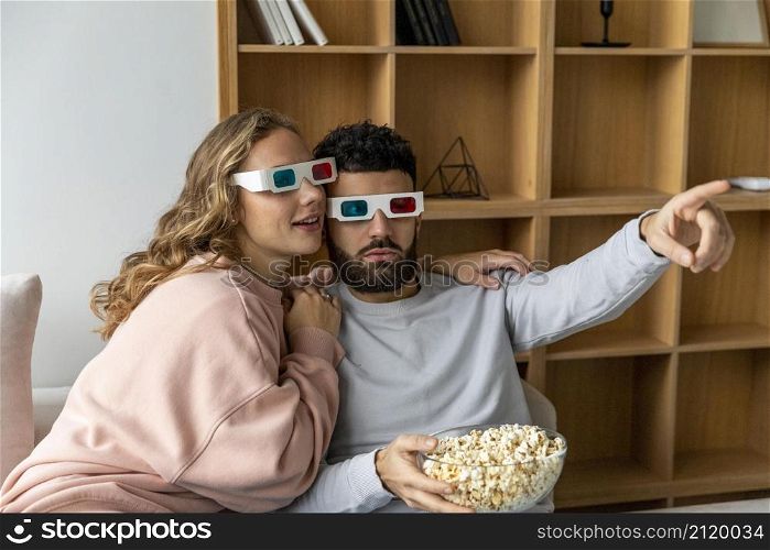 couple watching movie home with three dimensional glasses eating popcorn