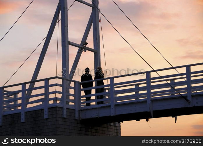 Couple watching sunset on a footbridge in Perkins Cove, Maine