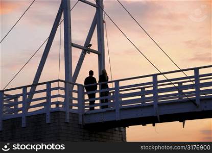 Couple watching sunset on a footbridge in Perkins Cove, Maine