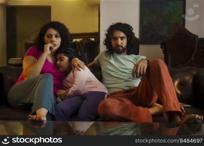Couple watching television while daughter sleeping on sofa in living room