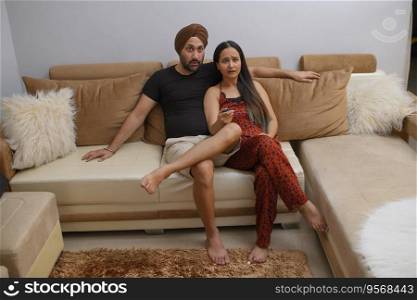 Couple watching TV while sitting on sofa in living room