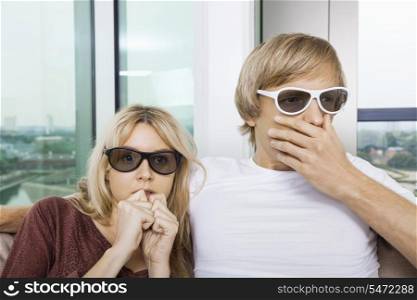 Couple wearing 3D glasses and watching TV with concentration at home