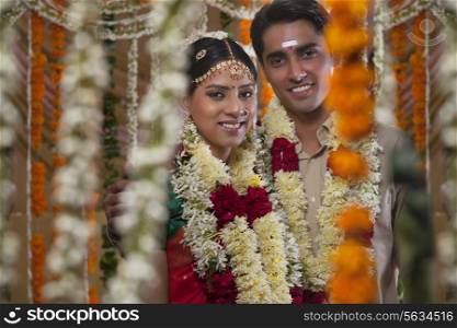 Couple wearing garlands standing together during traditional Indian wedding