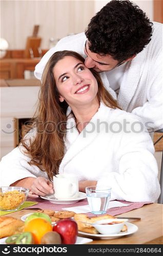Couple wearing matching bathing robes in kitchen