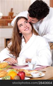 Couple wearing matching bathing robes in kitchen