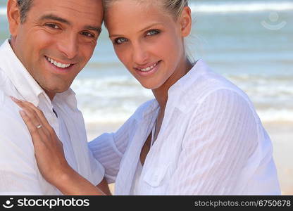 Couple wearing white clothing stood on a beach