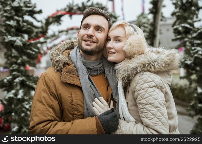 couple winter hugging looking away