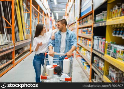 Couple with a cart buying building materials in hardware store. Customers look at the goods in diy shop