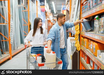 Couple with a cart choosing building materials in hardware store. Customers look at the goods in diy shop