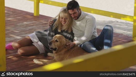 Couple With A Dog enjoying time together On The Beach at autumn day