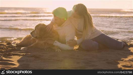 Couple With A Dog enjoying time together On The Beach at autumn day