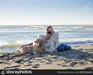 Couple With A Dog enjoying time together On The Beach at autumn day. Couple with dog enjoying time on beach