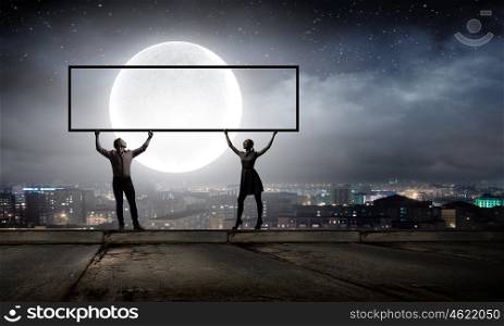 Couple with banner. Silhouettes of young couple holding banner above head