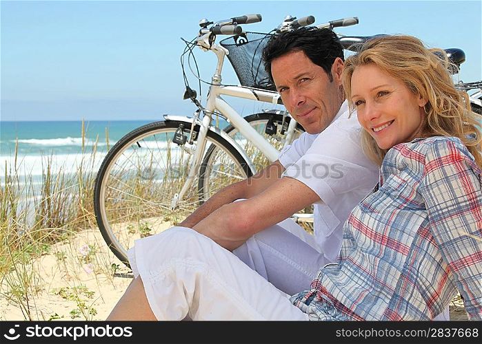 Couple with bikes sitting on the sand dunes
